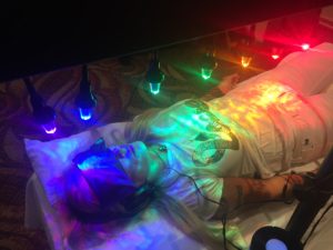 blindfolded person under 7 chakra lights from StellarWaves photon therapy